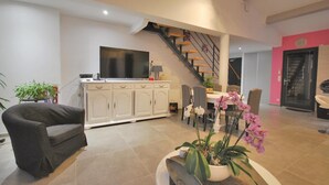A spacious living area with a sofa, a dining table with chairs, a kitchen area with a TV, and a staircase. - Amazing home in Callian (Callian)