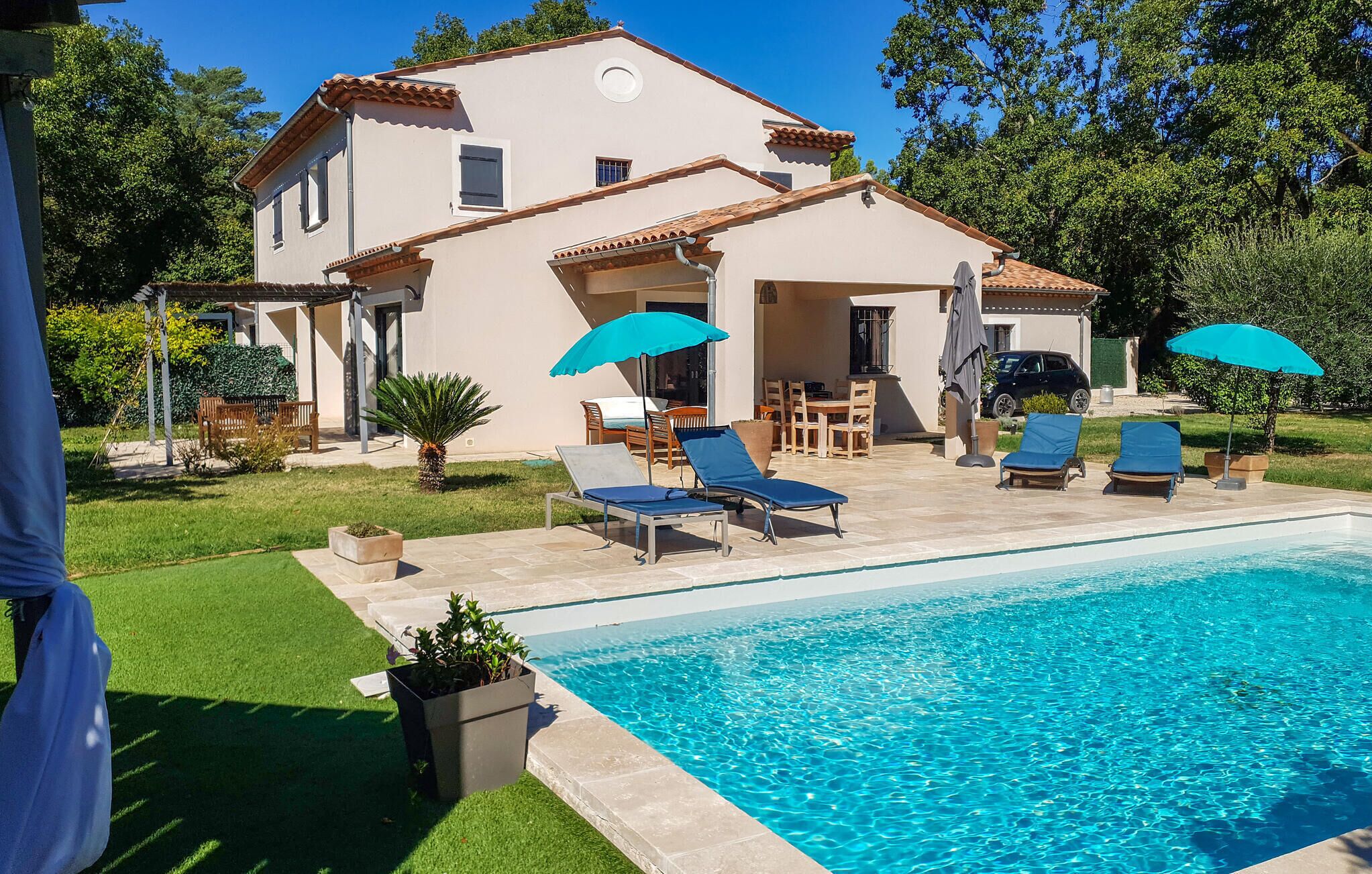 A two-story house with a swimming pool, outdoor furniture, and a garden.