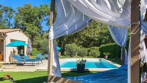 A covered outdoor area with a pool, lounge chairs, and a pergola with white drapes. - Amazing home in Callian (Callian)