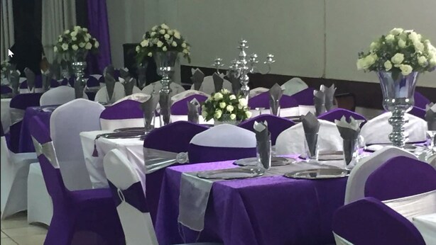 A banquet hall with tables set for a formal event, featuring purple tablecloths and white chairs with purple sashes. - Skyview Lodge At The Barn (Lusaka)
