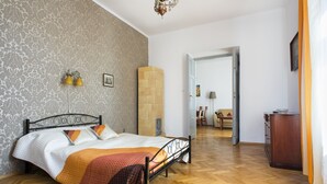 Una camera da letto con un letto, pavimento in legno, un armadio e una porta che dà su un'altra stanza.
