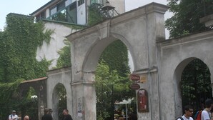 Un arco in pietra con cartelli che indicano camere in affitto.