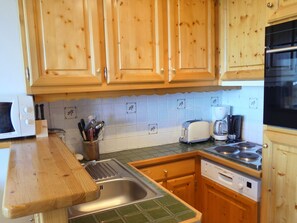 A kitchen with wooden cabinets, a microwave, a toaster, a coffee maker, and a dishwasher.
