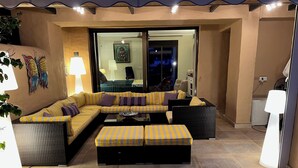 A cozy living area with a sofa set, a coffee table, and a side table. There is a large window with a view of the outside. - LUXURY MARBELLA DUPLEX OF 3 CH - 3 SDB - OF 155 M² + TERRACES 100 M²  (estepona)
