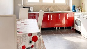 A kitchen with red cabinets, a white refrigerator, a microwave, and a sink. - Homerez - Comfortable Apartment with Garden (Saint-Dié-des-Vosges)