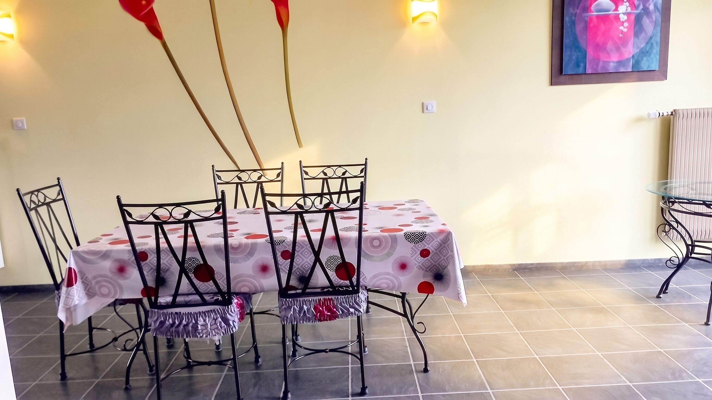 Un comedor con una mesa dispuesta para cuatro personas, rodeada de sillas de metal con diseños elaborados.
