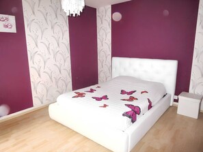 Cozy retreat with a butterfly-themed bedspread, a white headboard, and a nightstand.