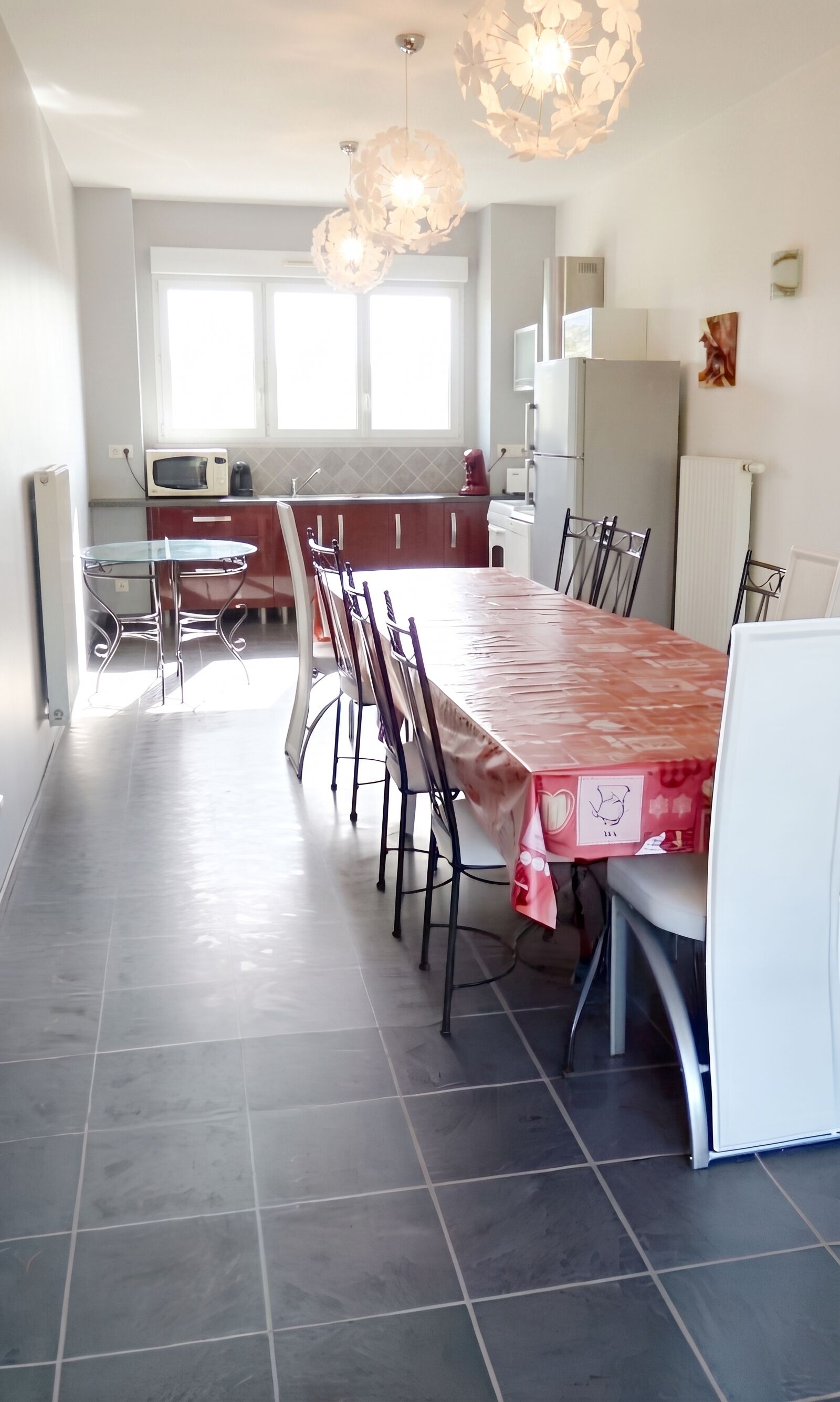 Una cocina moderna con comedor, que incluye una mesa larga, sillas y un refrigerador.
