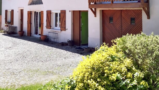 A two-story building with a balcony, a green door, and a gravel driveway. - Homerez - Comfortable Apartment with Garden (Saint-Dié-des-Vosges)