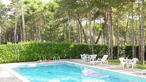 A rectangular swimming pool with clear blue water, surrounded by white lounge chairs and a hedge. - Lignano Exclusive With Pool (Lignano Sabbiadoro)