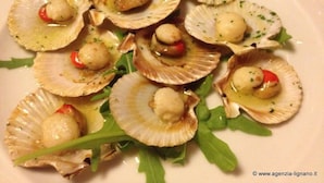 A plate of cooked scallops with cherry tomatoes and herbs. - Lignano Exclusive With Pool (Lignano Sabbiadoro)