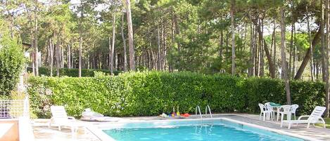 En säsongsöppen utomhuspool och solstolar