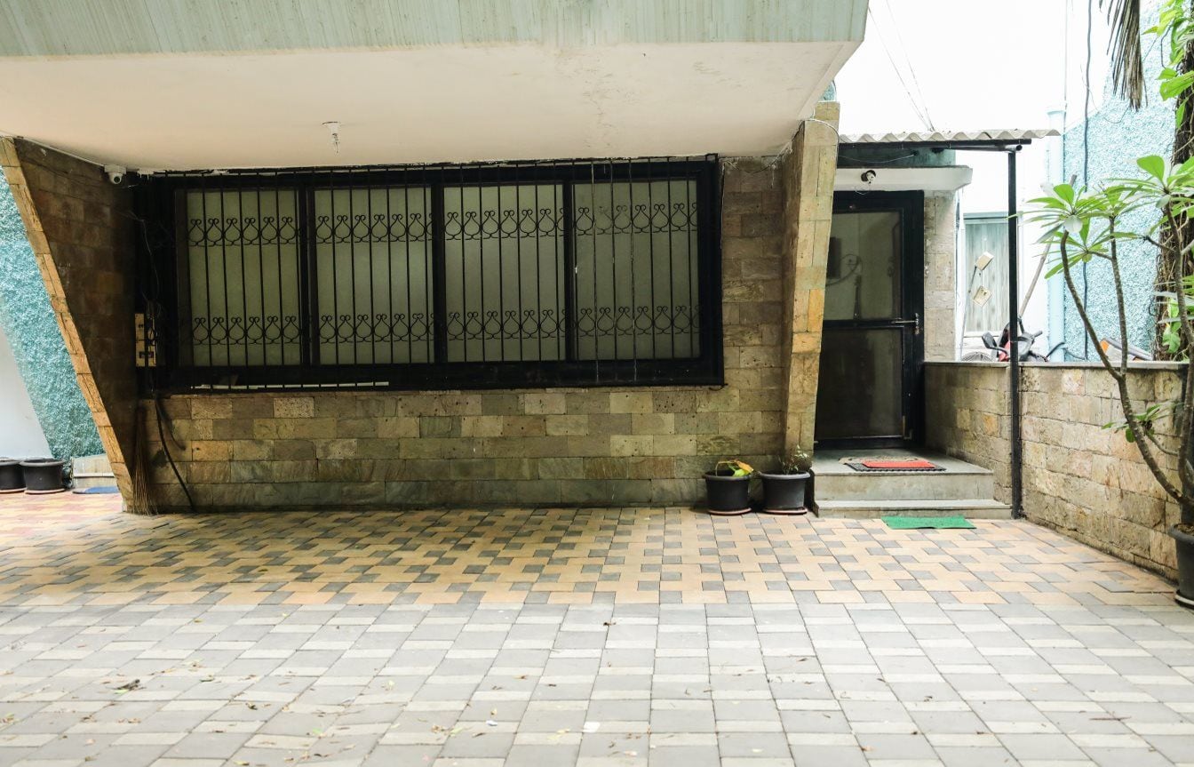Un patio con piso de baldosas, una reja metálica y un pequeño acceso con escalones.