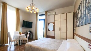 Hotellihuone, jossa on sänky, työpöytä tuolilla, televisio ja vaatekaappi.