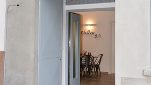 A doorway leading to a room with a table and chairs, a wall-mounted light, and a door with a number above it. - Civico29 B&B (Como)