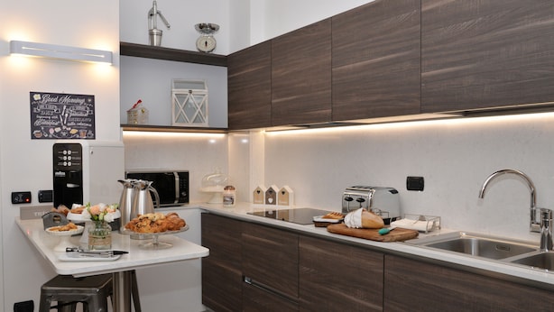 A modern kitchen with dark wood cabinets, stainless steel appliances, and a breakfast bar. - Civico29 B&B (Como)