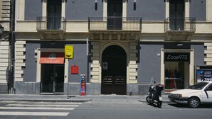 Un bâtiment avec une devanture de magasin, une moto garée devant et une voiture stationnée dans la rue.