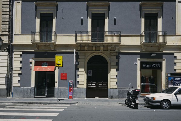 Un edificio con escaparate, una motocicleta estacionada adelante y un automóvil en la calle.