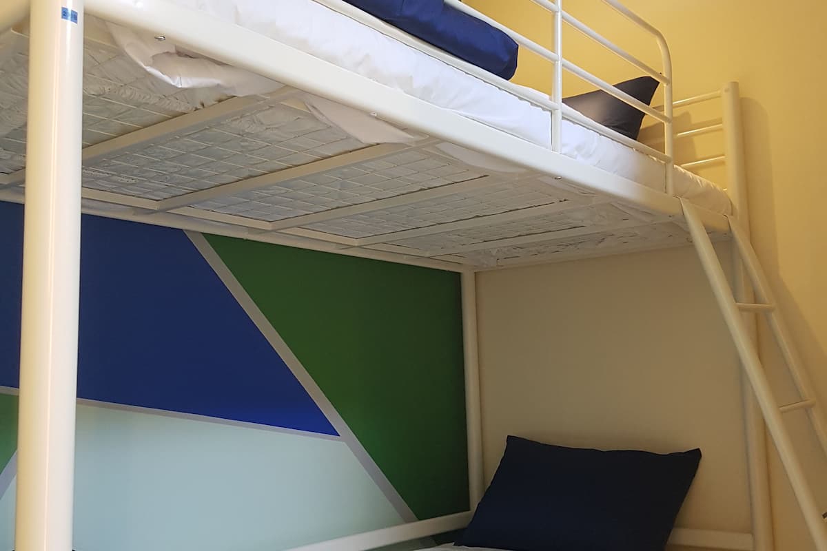 Ein Stockbett mit weißen Geländern und blauer Bettwäsche.
