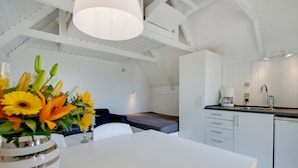 Una cocina moderna con armarios blancos, una mesa de comedor y un sofá.