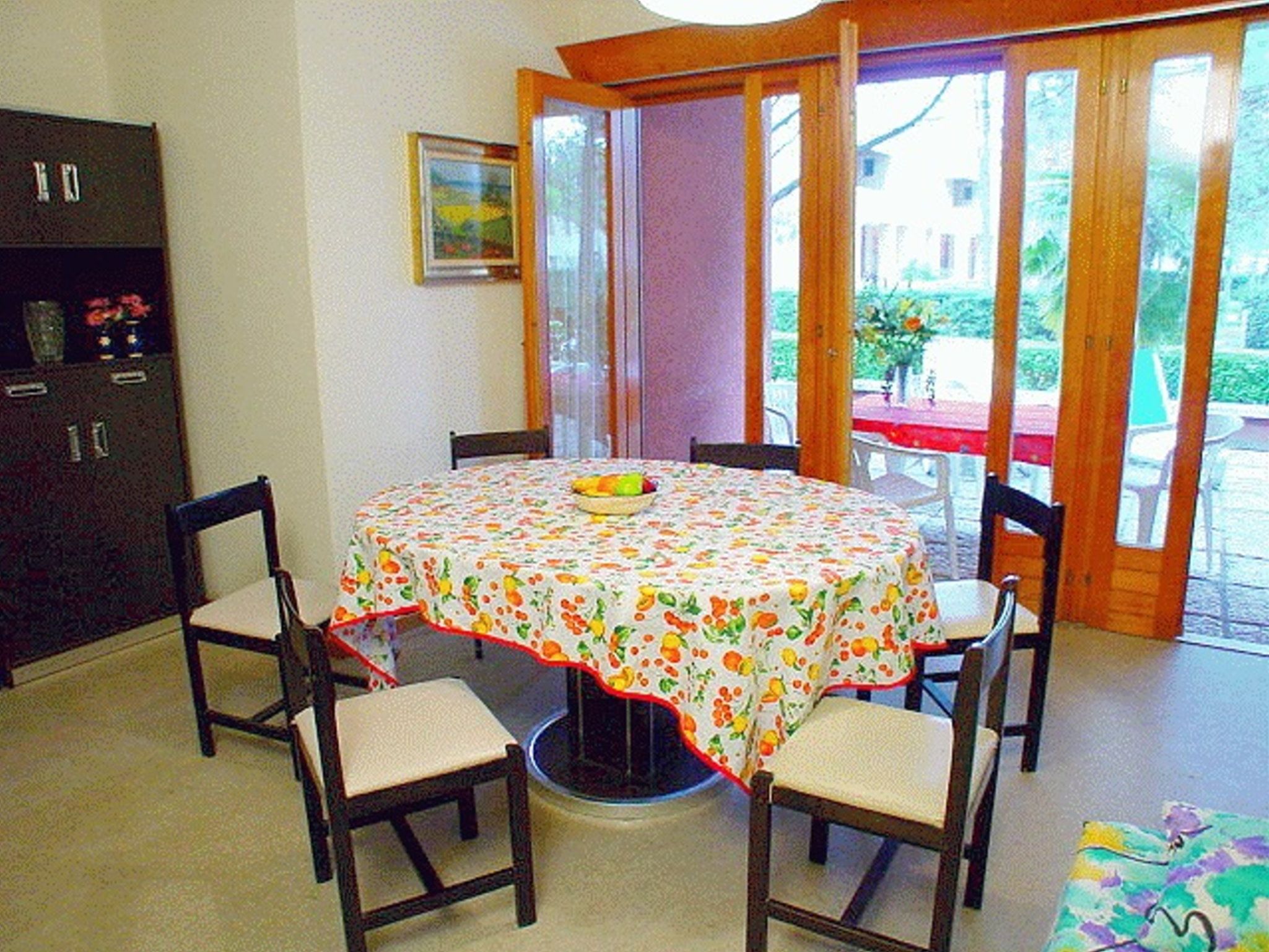 Un coin repas avec une table ronde recouverte d’une nappe à motifs floraux, entourée de quatre chaises.