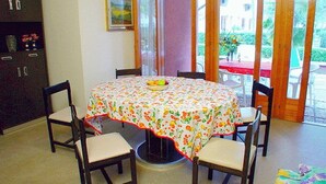 A dining area with a round table covered by a floral tablecloth, surrounded by four chairs.