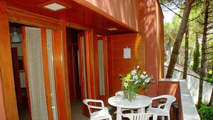 A patio with a round table and four white chairs, a vase with flowers, and a brick floor.