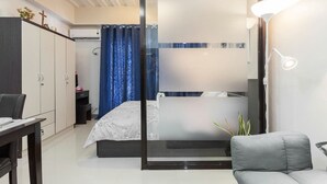 Un dormitorio moderno con cama, escritorio, armario y baño con bañera y ducha.