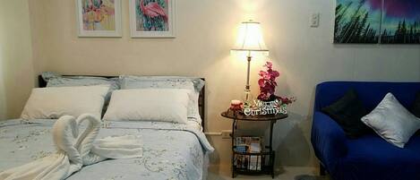 Una camera da letto con un letto, un divano blu, un comodino con una lampada e decorazioni alle pareti.