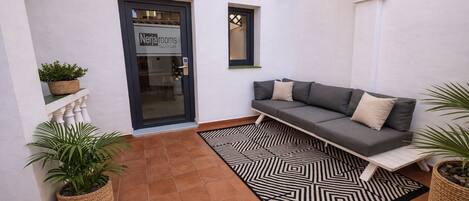 Un espacio al aire libre acogedor con un sofá, plantas en macetas y un tapete estampado.