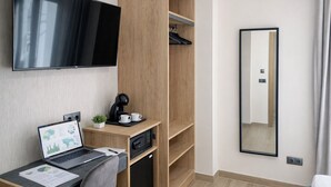 A modern hotel room with a flat-screen TV, a desk with a laptop, a coffee maker, a microwave, and a wardrobe. - NerjaRooms (Nerja)
