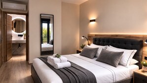 A modern bedroom with a large bed, a bedside table, a mirror, and a view of a bathroom. - NerjaRooms (Nerja)