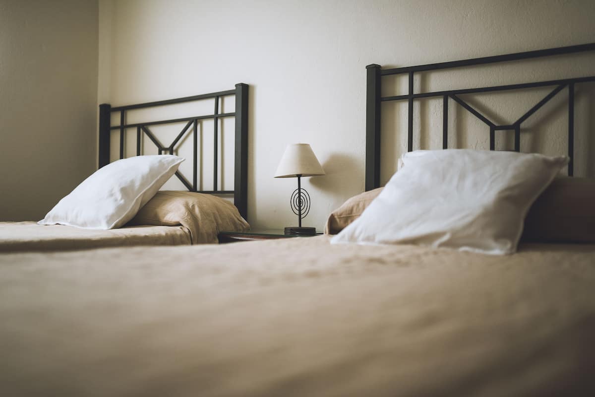 Un lit double avec une tête de lit, une table de chevet avec une lampe et deux oreillers.