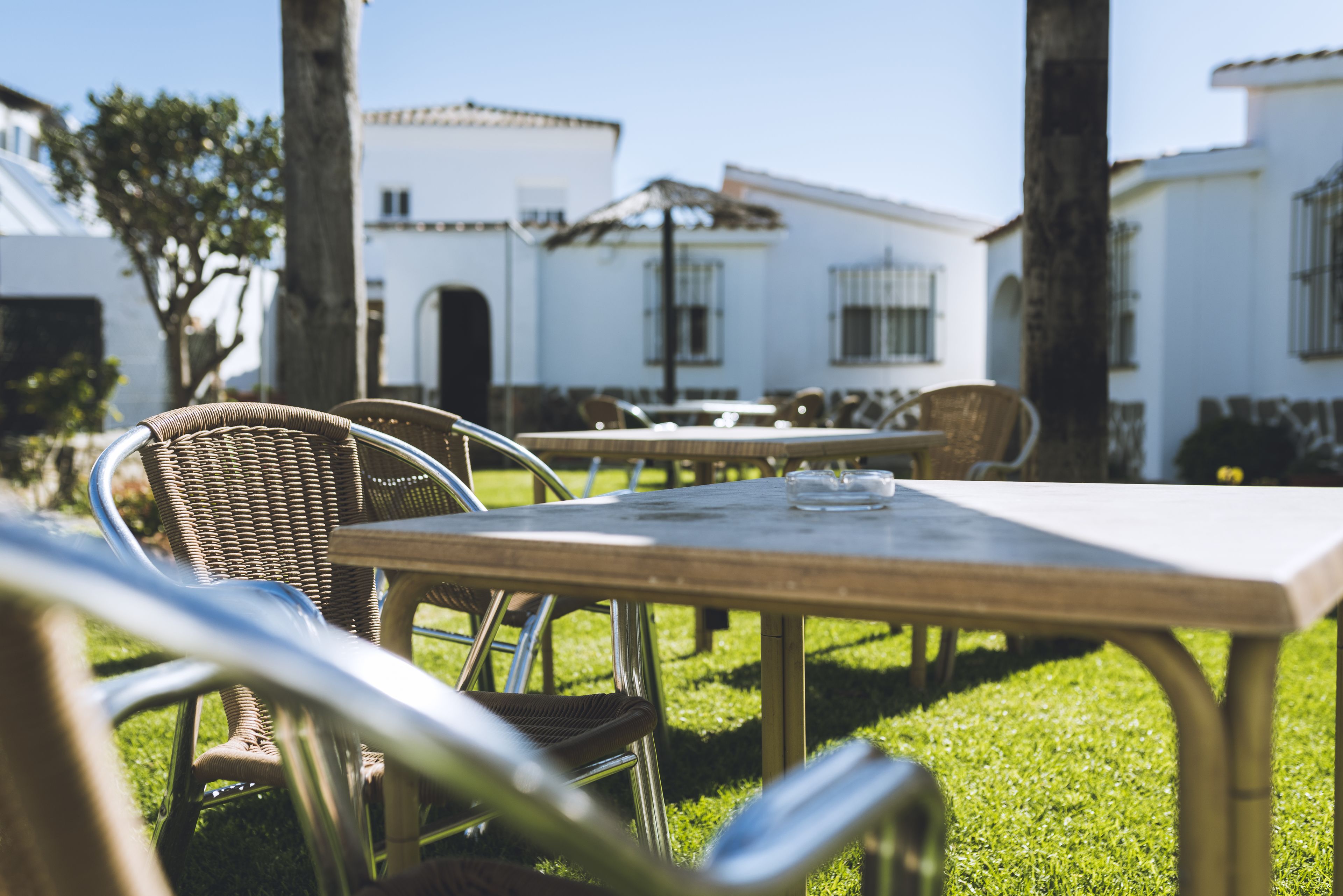 An outdoor patio with wicker chairs and a table, surrounded by white buildings with balconies.