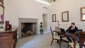 A room with a fireplace, a desk with a laptop, and a chandelier. - Residenza d'Epoca la Basilica by Mamo Florence (Florence)