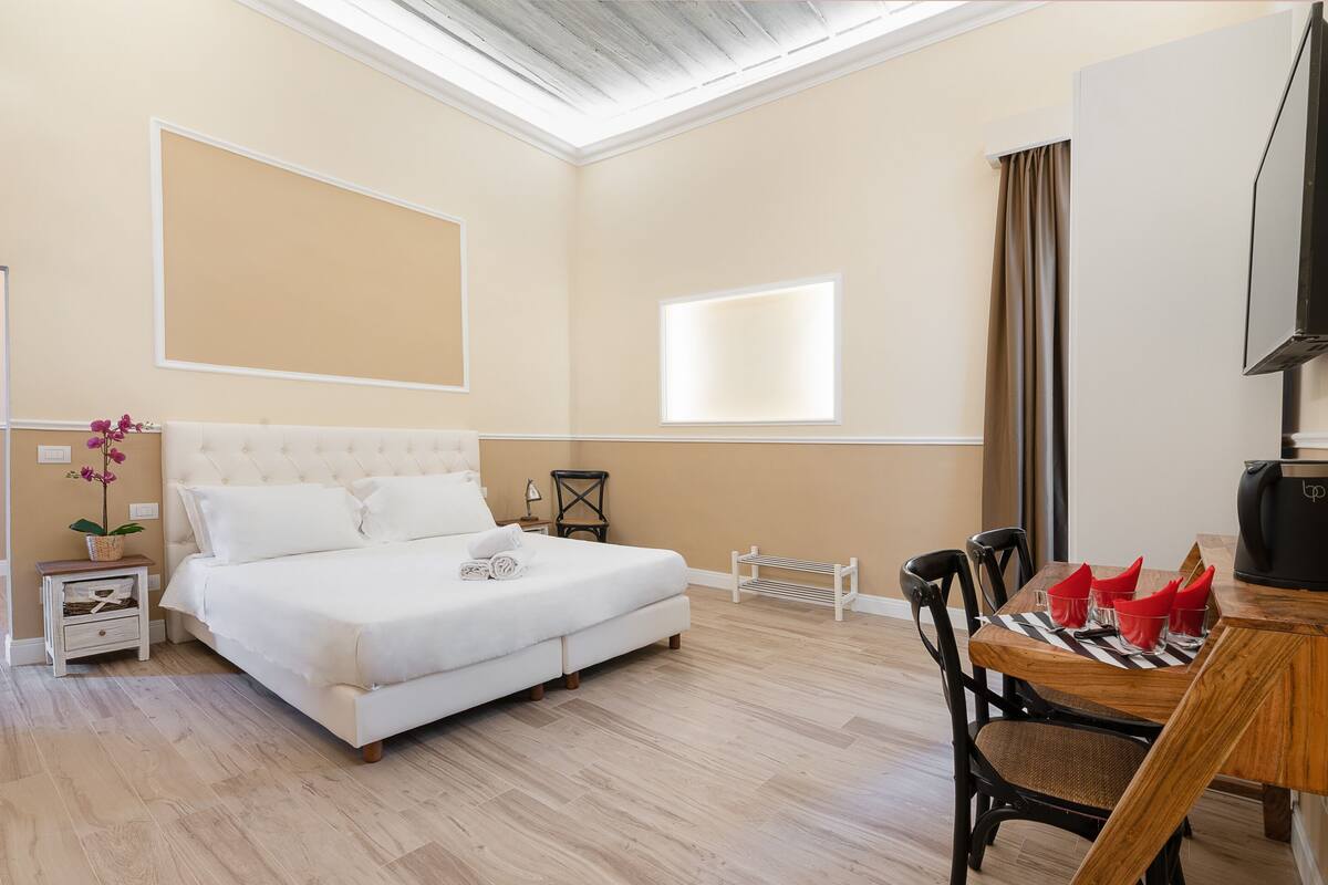 A bedroom with a bed, bedside table, lamp, and a window.