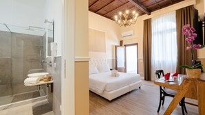 A hotel room with a shower, bed, and a dining area with a table and chairs. - Residenza d'Epoca la Basilica by Mamo Florence (Florence)