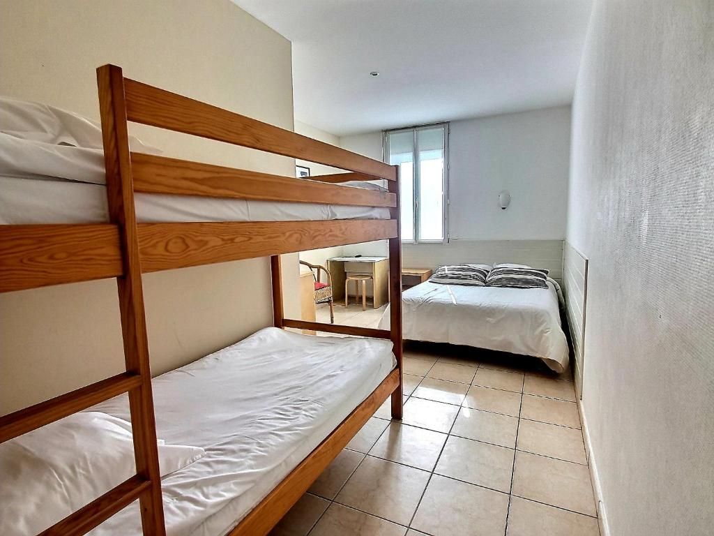 Una habitación con dos literas, una mesita pequeña y una ventana.