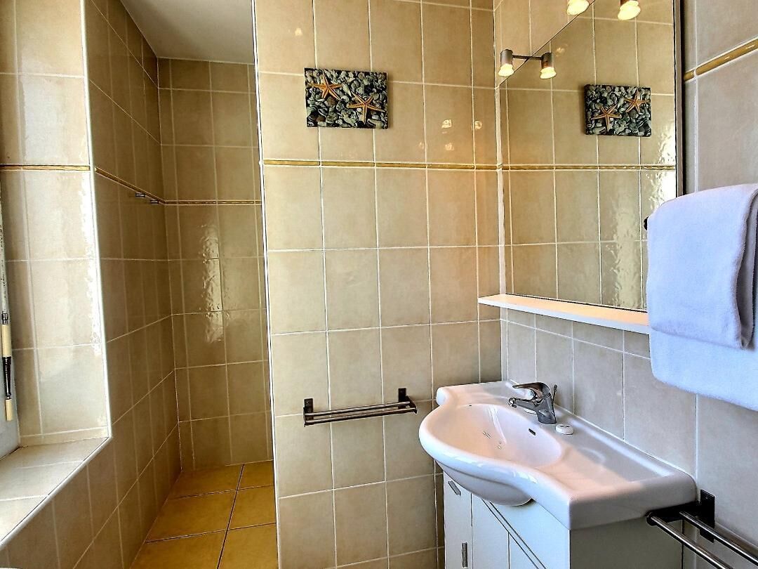 Een badkamer met beige tegels, een witte wastafel, een handdoekhouder en twee decoratieve wanddecoraties.