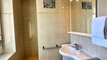 Een badkamer met beige tegels, een witte wastafel, een handdoekhouder en twee decoratieve wanddecoraties.