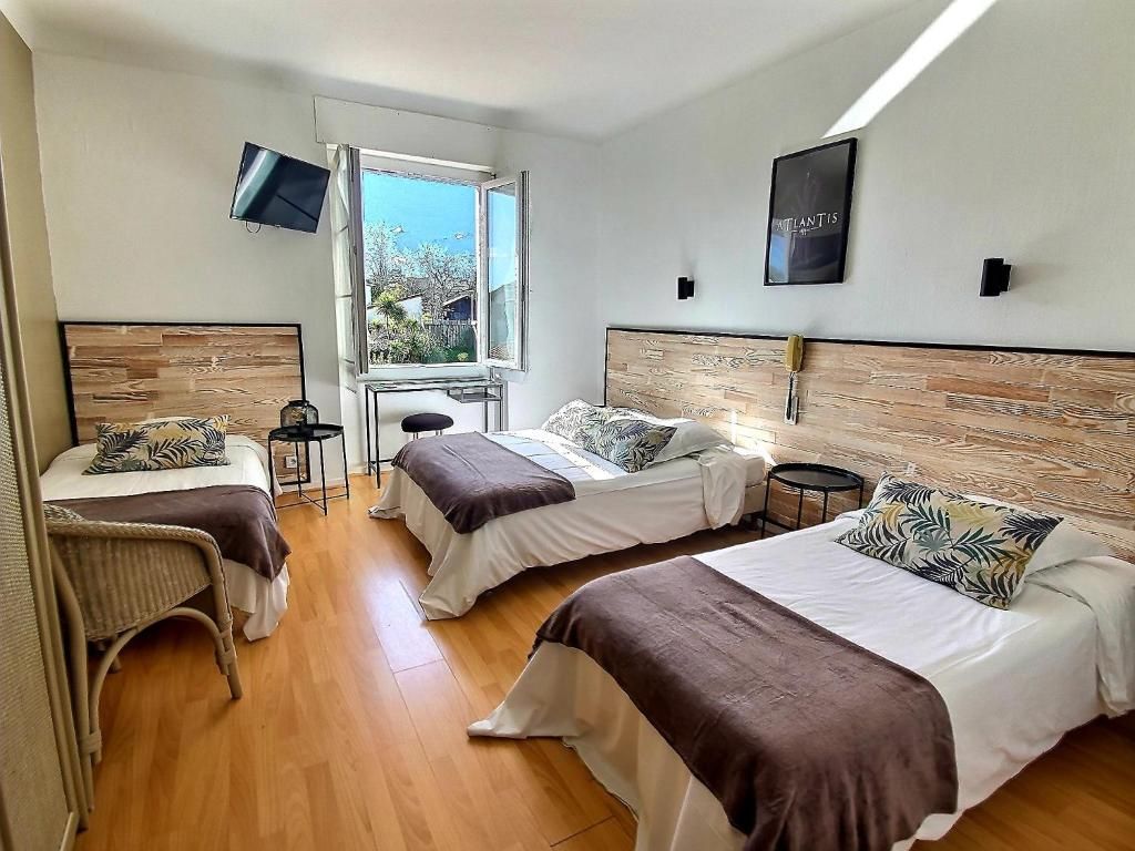Habitación de hotel con dos camas, televisión, ventana y un cuadro en la pared.