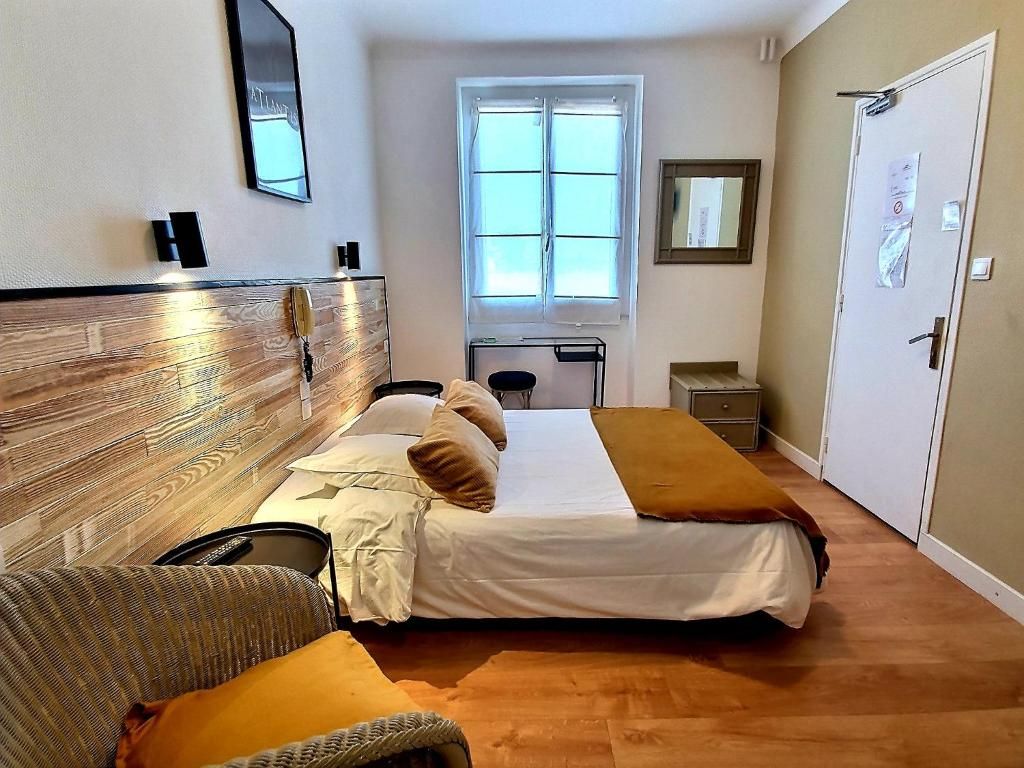 Een hotelkamer met een bed, een bureau, een stoel, een kledingkast en een raam.