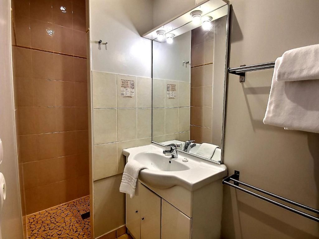 Une salle de bain équipée d’un lavabo, d’un miroir, d’un porte-serviettes et d’un espace douche.