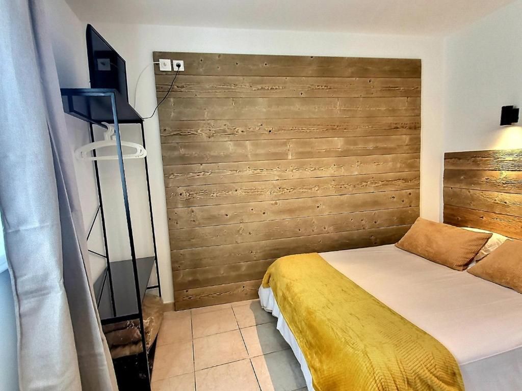 A bedroom with a bed, a wooden headboard, a TV, and a bedside table.