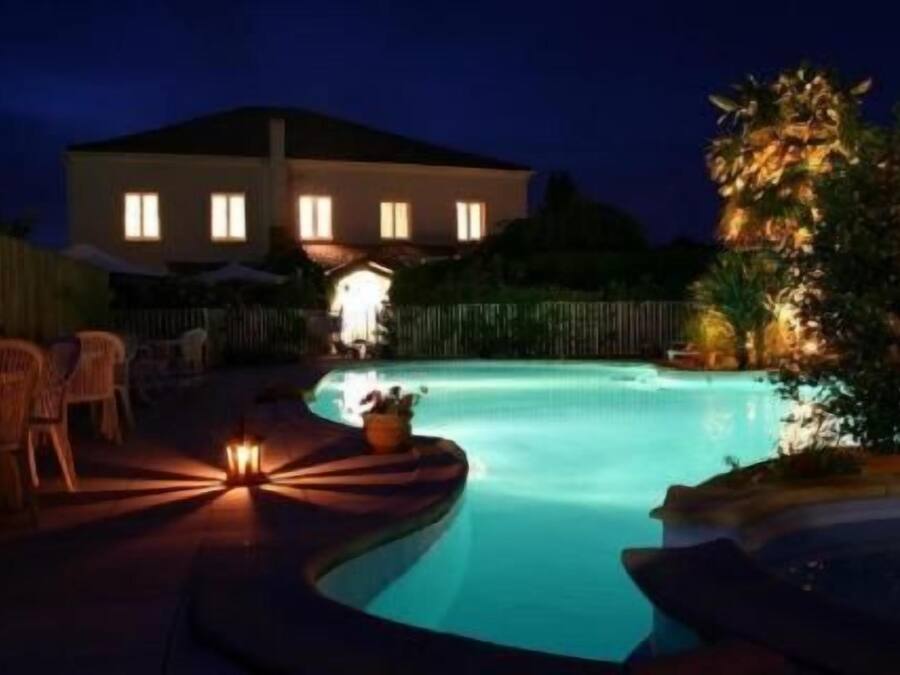 A swimming pool at night with a house in the background.