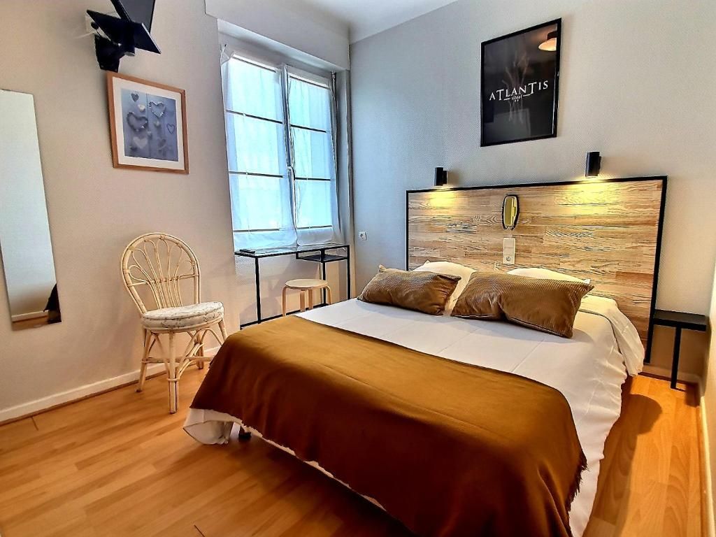 A bedroom with a bed, a chair, a window, and a wall-mounted picture.