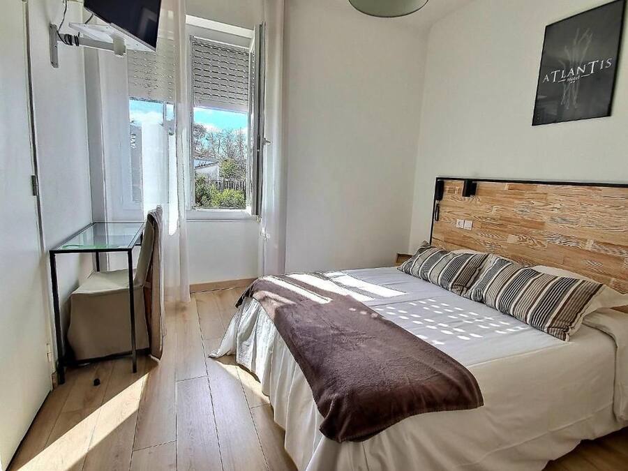 A bedroom with a bed, a bedside table, a chair, and a window.