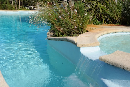 Una piscina al aire libre, sillones reclinables de piscina