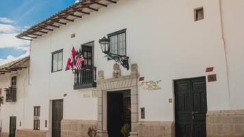 Traditional building with a charming entrance, featuring a balcony with a lantern and flags.