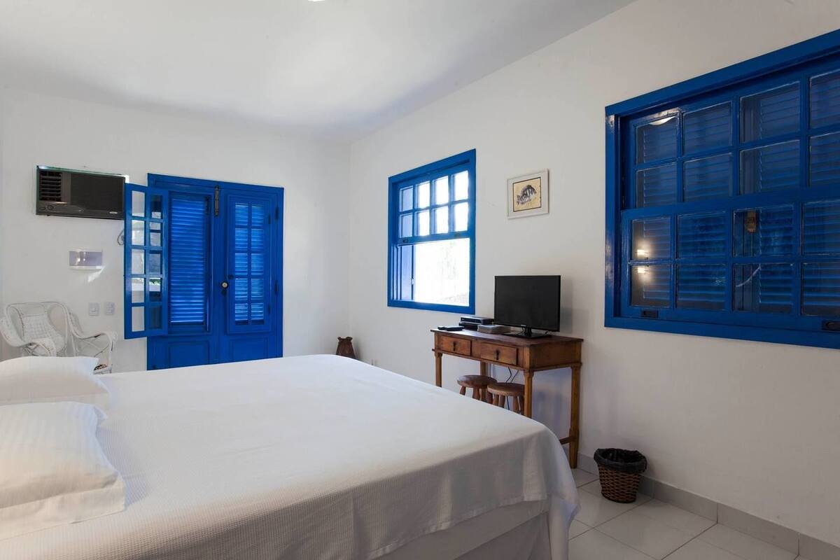 Un dormitorio con cama, escritorio y ventanas con marco azul.